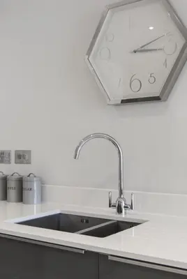 a kitchen with a sink and a clock on the wall at Citystay Living - Vesta Apartments in Cambridge