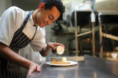 a man in a kitchen preparing food on a plate at Crown & Punchbowl in Cambridge