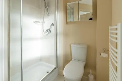 a white bathroom with a shower and a toilet at Camstay New Street in Cambridge