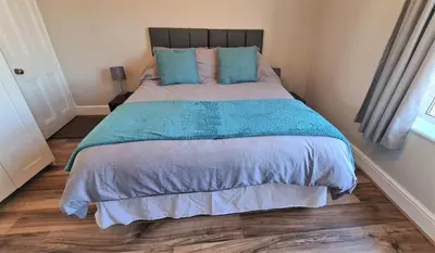 a bedroom with a large bed with blue sheets and blue pillows at Castle Cottage in Rayleigh