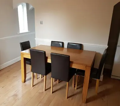 a dining room table with black chairs around it at Castle Cottage in Rayleigh