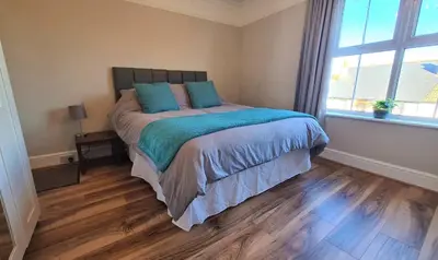 a bedroom with a bed with blue pillows and a window at Castle Cottage in Rayleigh