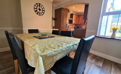 a dining room table with black chairs and a table cloth at Castle Cottage in Rayleigh