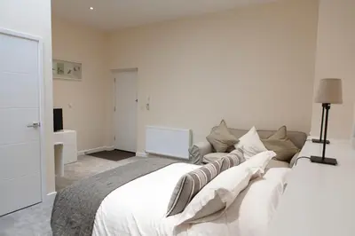 a white bedroom with a large bed with white pillows at Toothbrush Apartments - Ipswich Central East in Ipswich