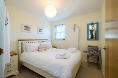 a bedroom with a white bed and a chair at Seascape in Aldeburgh