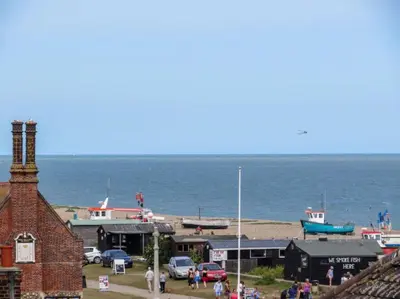 a group of people standing around a harbor with the ocean at Seascape in Aldeburgh