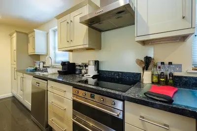a kitchen with white cabinets and a black counter top at Seascape in Aldeburgh