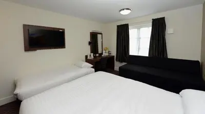 a bedroom with two beds and a tv on the wall at Mermaid, Ipswich by Marston's Inns in Ipswich