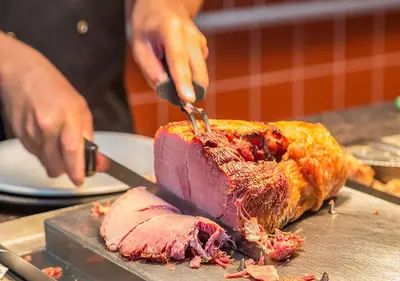 a person cutting a piece of meat with a knife at Mermaid, Ipswich by Marston's Inns in Ipswich
