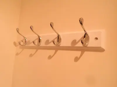 a shelf with three hooks on a wall at Old School House Studio in Stetchworth