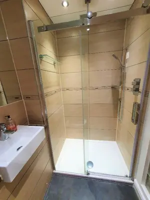 a shower with a glass door next to a sink at Old School House Studio in Stetchworth