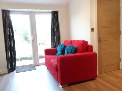 a red couch in a room with a window at Old School House Studio in Stetchworth