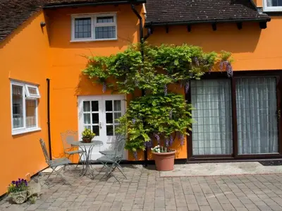 an orange house with a table and chairs in front of it at Woodview B Colchester in Birch