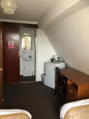 a room with a desk and a table and a sink at Fairways Guest House in Cambridge