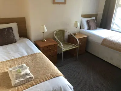 a hotel room with two beds and a chair at Fairways Guest House in Cambridge