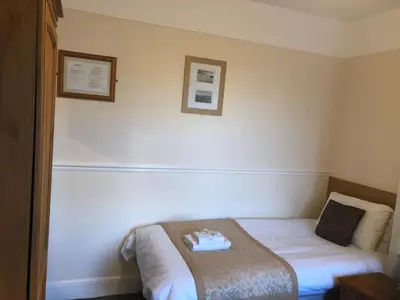 a hotel room with a bed and two pictures on the wall at Fairways Guest House in Cambridge