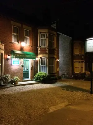 a building with a green sign on it at night at Fairways Guest House in Cambridge