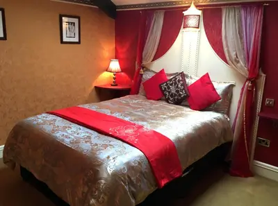 a bedroom with a large bed with red walls at The PitStop in Bishops Stortford