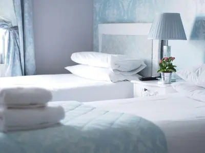 two beds with white sheets and a lamp in a room at The Cambridge Guest House by Tas in Cambridge
