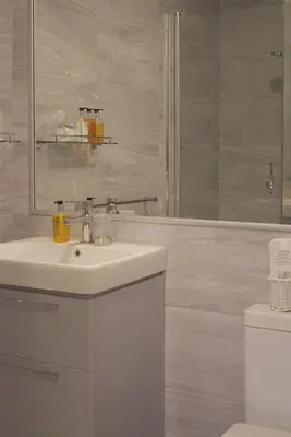 a white bathroom with a sink and a shower at The Cambridge Guest House by Tas in Cambridge