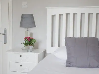 a white bedroom with a bed with a pillow and a lamp at The Cambridge Guest House by Tas in Cambridge