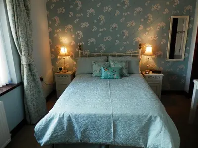 a bedroom with a bed with a blue bedspread at Finjaro in Sproughton
