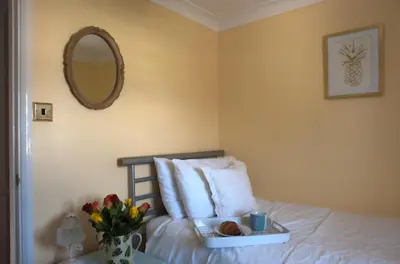 a bedroom with a bed with a mirror and flowers at Little Chequers in Friston