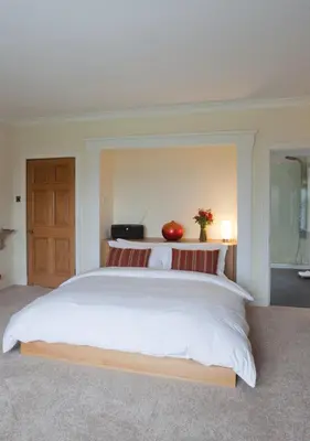 a bedroom with a large white bed with a wooden headboard at Sturmer Hall Hotel and Conference Centre in Haverhill