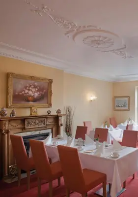 a dining room with tables and chairs and a fireplace at Sturmer Hall Hotel and Conference Centre in Haverhill