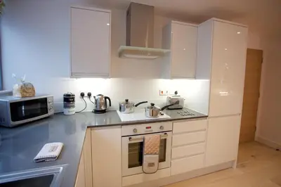 a kitchen with white cabinets and a stove top oven at Citystay Living - Pringle House in Cambridge