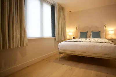 a bedroom with a bed with blue pillows and a window at Citystay Living - Pringle House in Cambridge