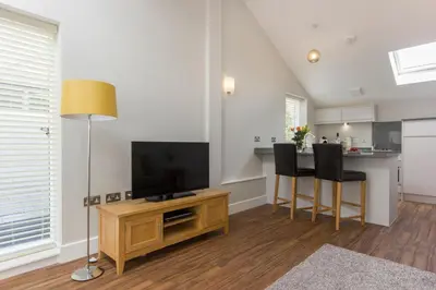 a living room with a television and a table with chairs at Citystay Living - The Dales in Cambridge
