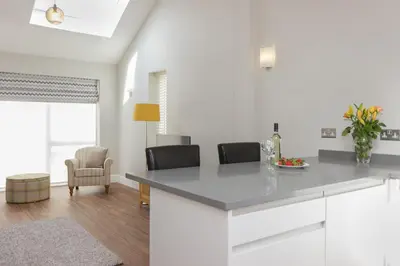 a kitchen with white cabinets and a table and chairs at Citystay Living - The Dales in Cambridge