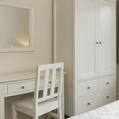 a white bedroom with a white chair and a dresser at Citystay Living - Citygate in Cambridge