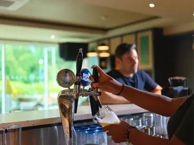 a woman is filling a glass at a bar at B&B HOTEL Ipswich in Ipswich