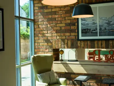 a living room with a brick wall and a chair at B&B HOTEL Ipswich in Ipswich