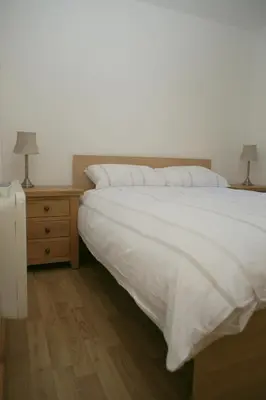 a bedroom with a bed and a nightstand with two lamps at The Elms Annex in Cottered