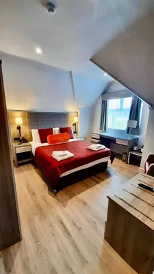 a bedroom with a large bed with a red blanket at Hotel Coco in Felixstowe