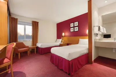 a hotel room with two beds and a sink at Days Inn Stevenage North in Baldock