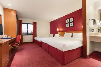 a hotel room with a large bed and a desk at Days Inn Stevenage North in Baldock