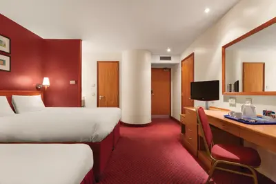 a hotel room with two beds and a desk at Days Inn Stevenage North in Baldock