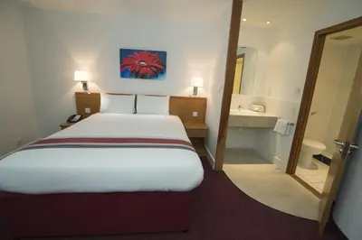a hotel room with a bed and a bathroom at Ramada Cambridge in Cambridge