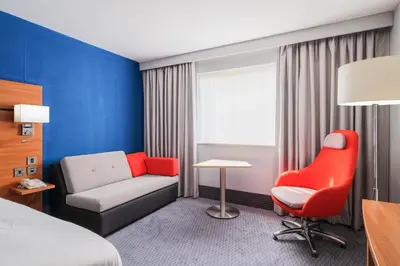 a hotel room with a bed and a red chair at Holiday Inn Express Braintree by IHG in Braintree