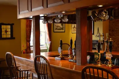 a bar in a restaurant with chairs around it at The Crown Inn Hotel in Long Melford