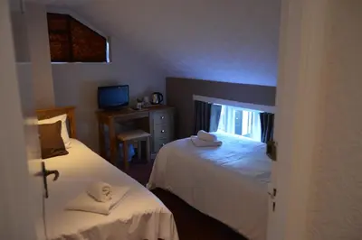 a bedroom with two beds and a desk and a window at The Crown Inn Hotel in Long Melford