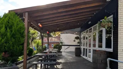 a patio with tables and chairs under a wooden pergola at The Park Hotel - Sure Hotel Collection by Best Western in Diss