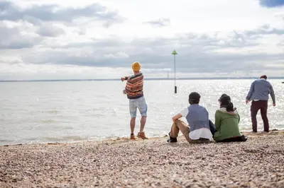 a group of people sitting on the beach near the water at University of Essex - Southend Campus in Southend-on-Sea