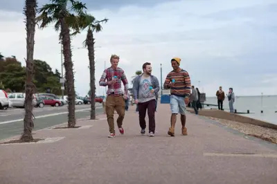 three men walking down a sidewalk near the beach at University of Essex - Southend Campus in Southend-on-Sea