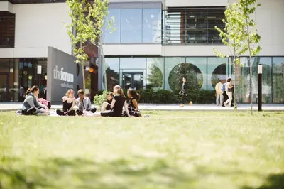a group of people sitting on the grass in front of a building at University of Essex - Southend Campus in Southend-on-Sea