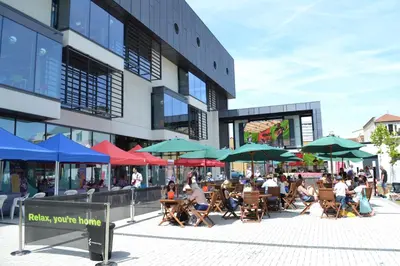 a group of people sitting outside of a building with umbrellas at University of Essex - Southend Campus in Southend-on-Sea